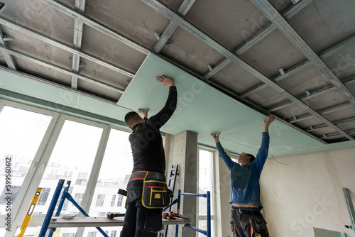 Φωτογραφία Workers fitting panel into frame of ceiling.