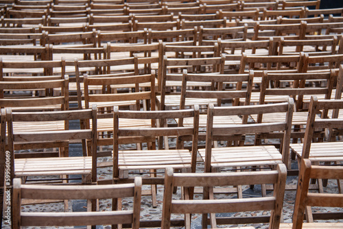 Many open wooden chairs, close up, on a cloudy day.