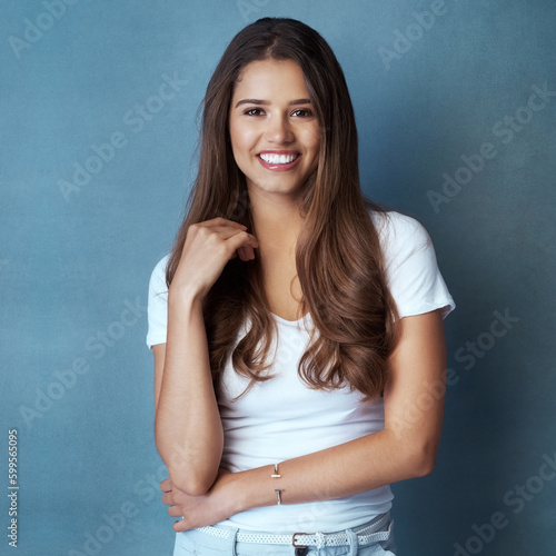 Confident is beautiful, wear it daily. Studio shot of an attractive young woman posing against a blue background.