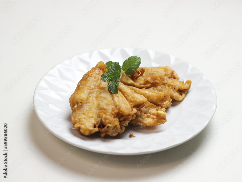 Banana fritters in white ceramic plate. In Indonesia it called pisang goreng kipas. selective focus Banana fritters in white ceramic plate. In Indonesia it called pisang goreng kipas. selective focus