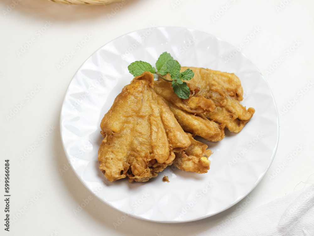 Banana fritters in white ceramic plate. In Indonesia it called pisang goreng kipas. selective focus Banana fritters in white ceramic plate. In Indonesia it called pisang goreng kipas. selective focus