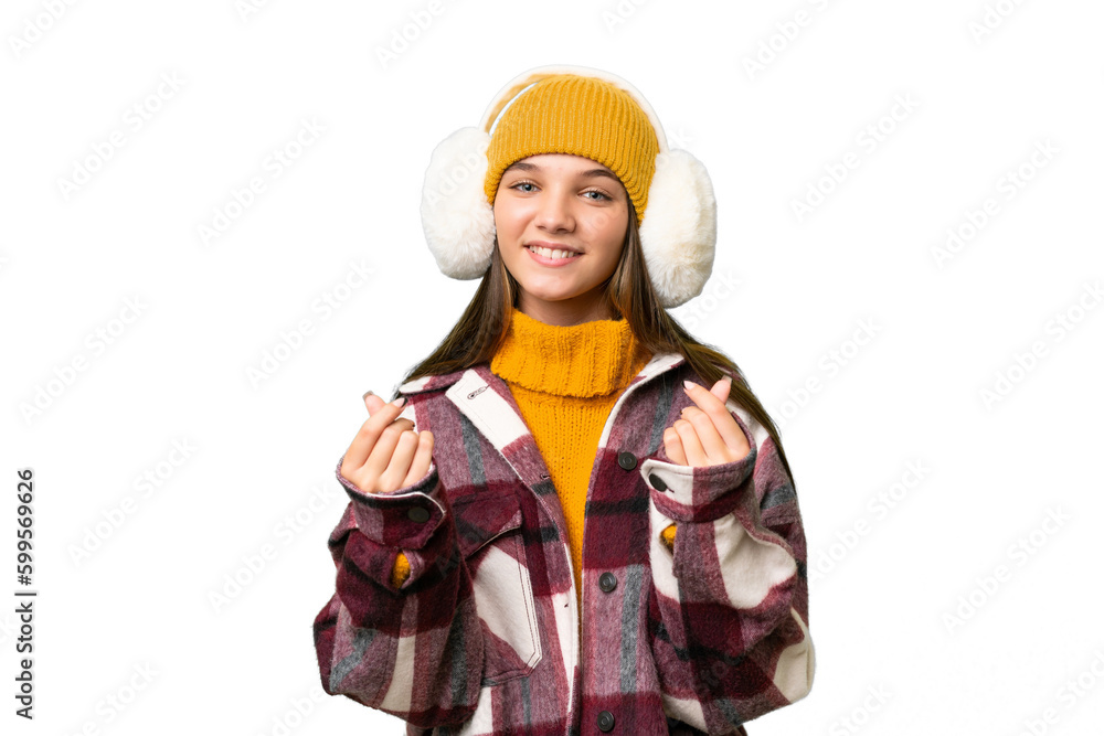Teenager caucasian girl wearing winter muffs over isolated background making money gesture Teenager caucasian girl wearing winter muffs over isolated background making money gesture