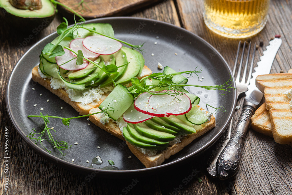 White bread toasts with cream cheese, avocado, cucumber and radish in a plate White bread toasts with cream cheese, avocado, cucumber and radish in a plate