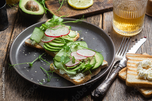 White bread toasts with cream cheese, avocado, cucumber and radish in a plate