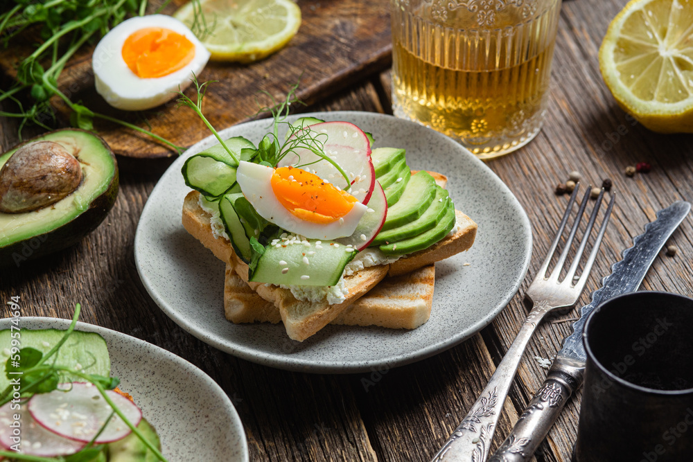 White bread toasts with cream cheese, egg, avocado, cucumber and radish in a plate White bread toasts with cream cheese, egg, avocado, cucumber and radish in a plate