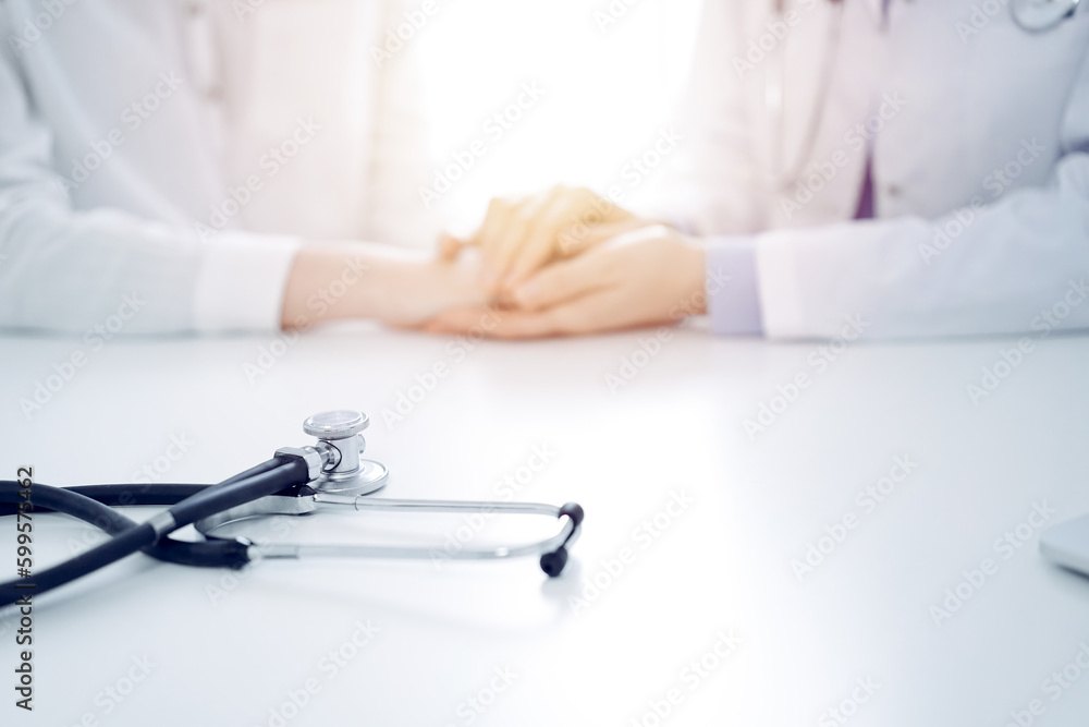 Stethoscope lying on the tablet computer in front of a doctor and patient sitting opposite each other at the background . Medicine, healthcare concept Stethoscope lying on the tablet computer in front of a doctor and patient sitting opposite each other at the background . Medicine, healthcare concept