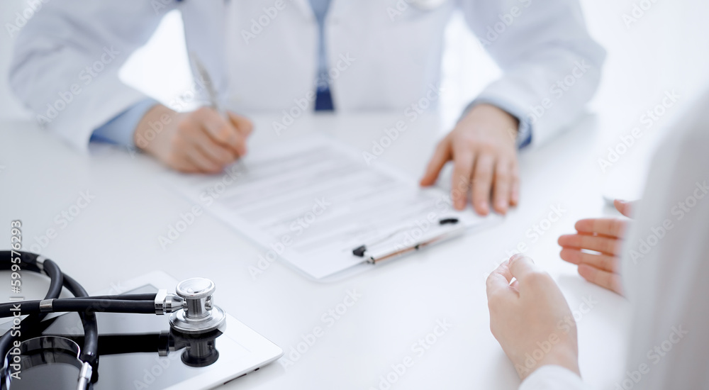 Stethoscope lying on the tablet computer in front of a doctor and patient sitting opposite each other at the background . Medicine, healthcare concept Stethoscope lying on the tablet computer in front of a doctor and patient sitting opposite each other at the background . Medicine, healthcare concept