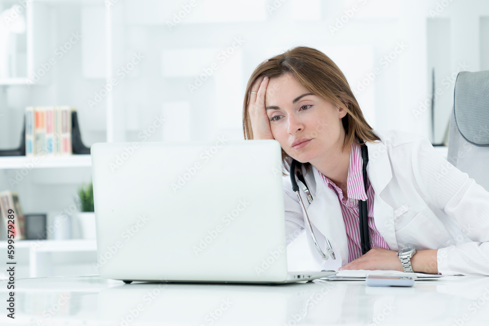 Young attractive female doctor sitting at the desktop in the office and consulting her patient online Young attractive female doctor sitting at the desktop in the office and consulting her patient online