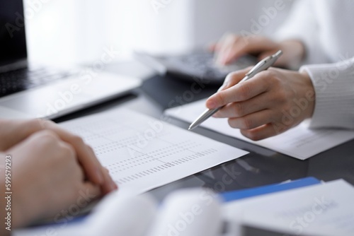 Woman accountant using a calculator and laptop computer while counting taxes for a client. Business audit and finance concepts