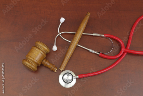 Red stethoscope and broken judge gavel on table. Doctor mistake and court concept.