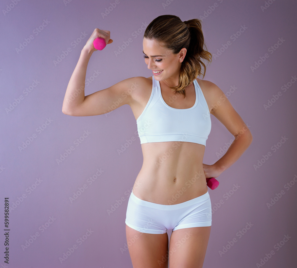 Small progress is still progress. Studio shot of a healthy young woman holding dumbbells posing against a purple background. Small progress is still progress. Studio shot of a healthy young woman holding dumbbells posing against a purple background.