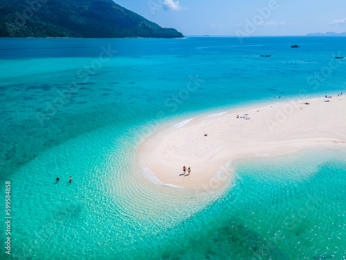 men and women walking on a sandbar in the ocean of Koh lipe Southern Thailand during vacation photo