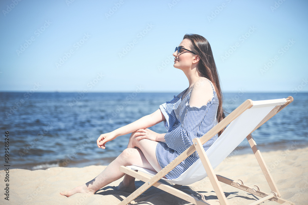 Portrait of a happy smiling brunette woman standing on ocean beach and looking at the camera
