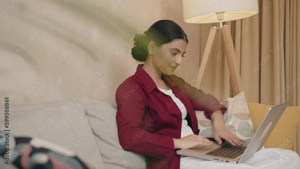 Serious woman using laptop checking email news online sitting on sofa Serious woman using laptop checking email news online sitting on sofa