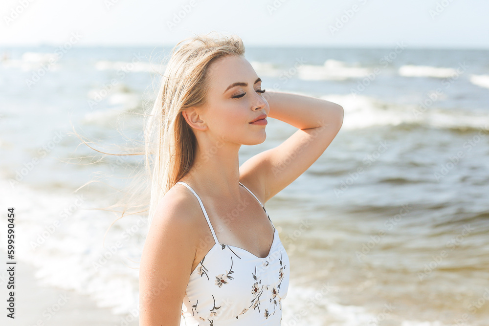 Happy blonde woman wearing sun glasses and relaxing on a wooden deck chair at the ocean beach Happy blonde woman wearing sun glasses and relaxing on a wooden deck chair at the ocean beach