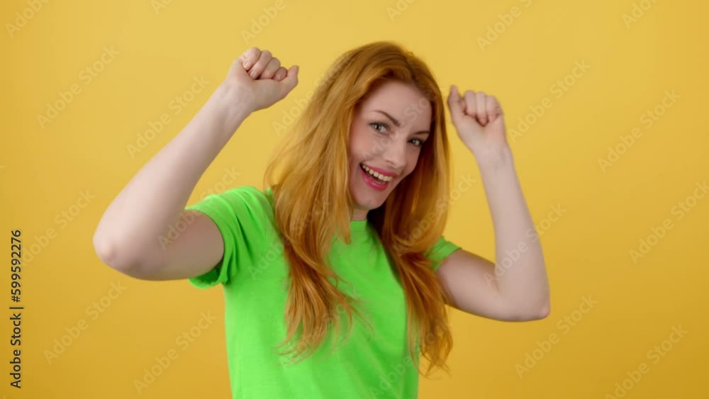 Yes gesture and winner woman smiling nodding, say Yes. Excited happy young redhead lady showing approving gesture, thumbs up, for victory, success. Indoor studio shot isolated on yellow background Yes gesture and winner woman smiling nodding, say Yes. Excited happy young redhead lady showing approving gesture, thumbs up, for victory, success. Indoor studio shot isolated on yellow background