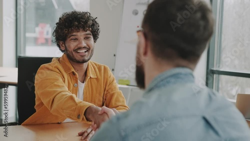 handshake and successful deal of multiethnic employees in the office at the table, Indian or latin employee shakes hands. Success at work and in business