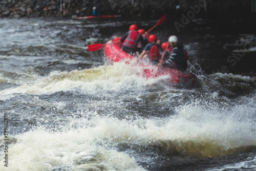 Red raft boat during whitewater rafting extreme water sports on water rapids, group of sportsmen in wetsuits kayaking and canoeing on the river, water sports team with a big splash of water