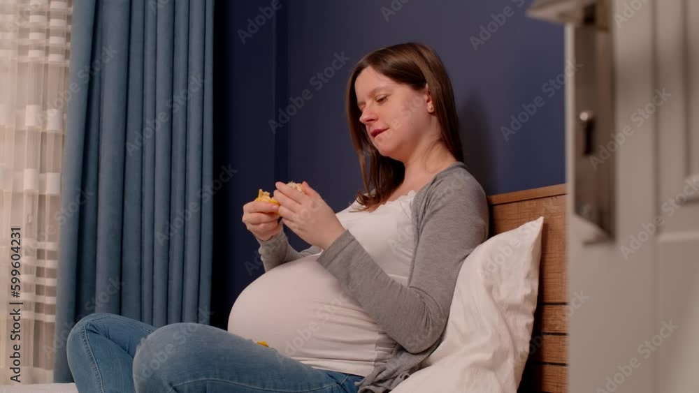 Pregnant woman sitting in bed and eating mandarin, healthy snack while you are expecting child. Always eating while pregnancy. Pregnant woman sitting in bed and eating mandarin, healthy snack while you are expecting child. Always eating while pregnancy.