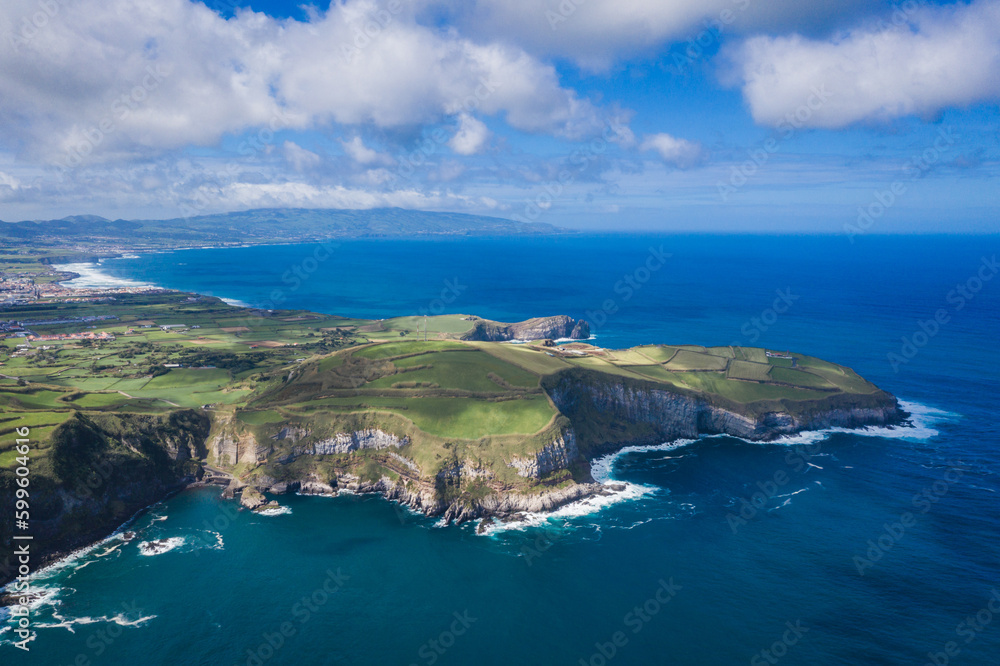 Aerial view of the coastline on Sao Miguel Island, with town buildings, green farmland and volcanic mountains, Azores, Portugal