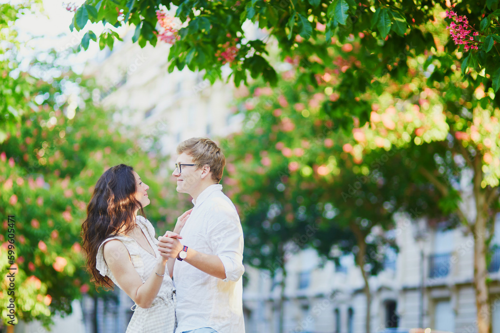 Happy romantic couple in Paris, hugging under pink chestnuts in full bloom Happy romantic couple in Paris, hugging under pink chestnuts in full bloom
