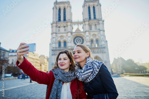 Two young girls taking selfie near Notre-Dame in Paris