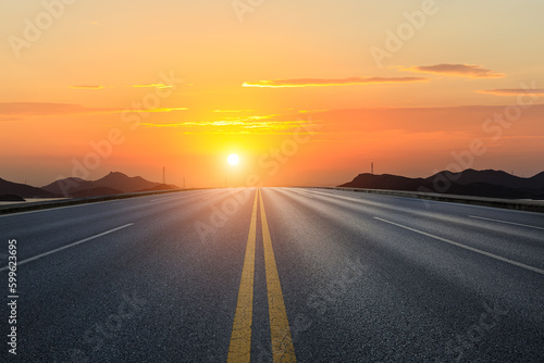 Straight asphalt road and mountain with sky clouds background at sunset © ABCDstock