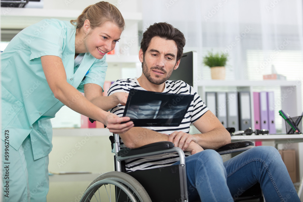 young female medic holding x-ray image showing to disabled patient young female medic holding x-ray image showing to disabled patient
