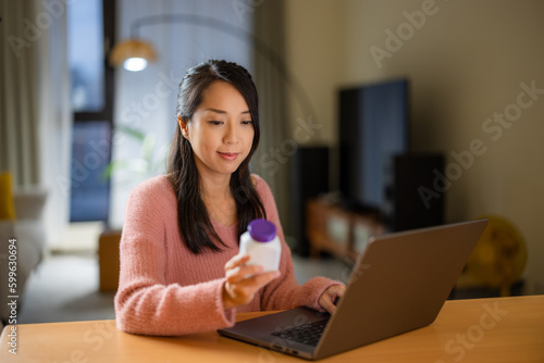 Woman use laptop computer to check the medicine at home