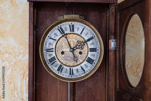 Old wooden clock with a pendulum hanging on the wall