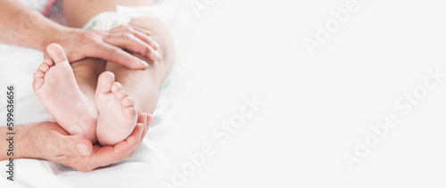 Grandmother showing legs of little baby on bed.