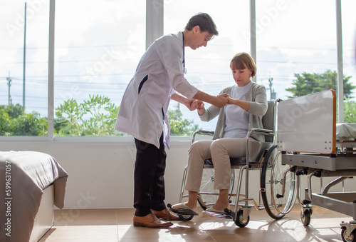 caucasian man doctor is examining the female older patient in wheelchair the hospital.