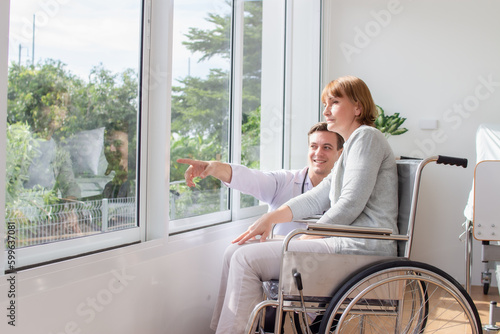 caucasian man doctor is examining the female older patient in wheelchair the hospital.