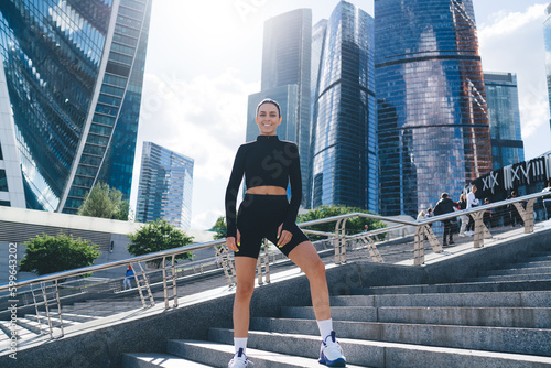 Positive female athlete standing on steps and smiling