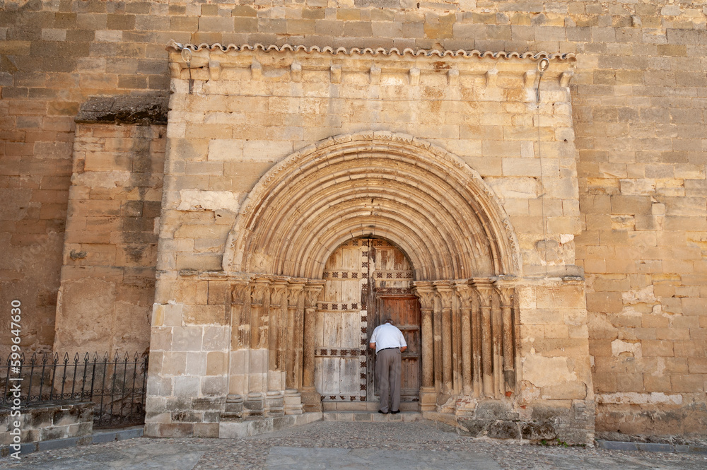 Un hombre abre la iglesia de Alcocer en Guadalajara con una excelente portada románica.