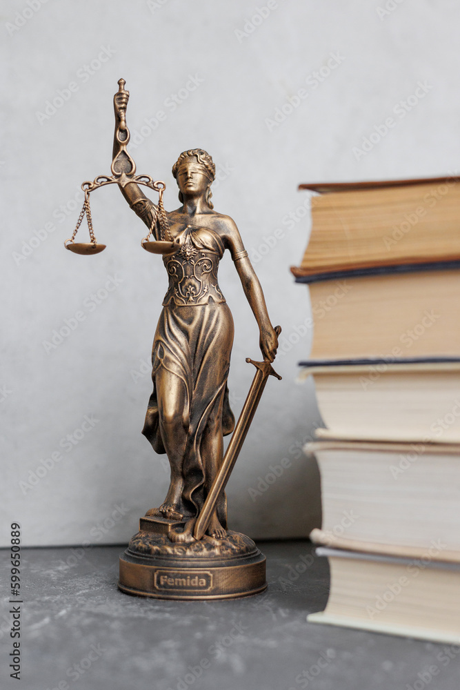 themis goddess of justice statuette on background of books on desktop. symbol of law with scales and sword in his hands. legal company or university of law and judicial structure. library education themis goddess of justice statuette on background of books on desktop. symbol of law with scales and sword in his hands. legal company or university of law and judicial structure. library education