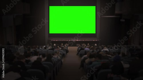 Crowd of people watch big green screen