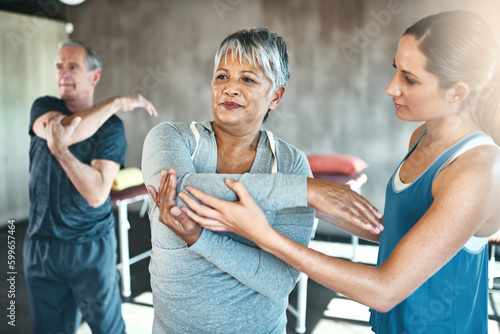Stretching, physiotherapy and old woman with personal trainer for fitness, wellness or rehabilitation. Health, workout or retirement with senior patient and female trainer in gym for warm up training