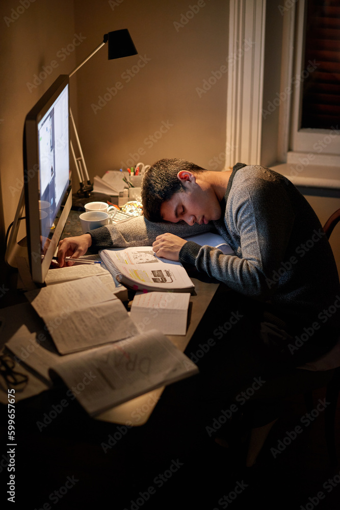 Student, books and sleep or studying late into the night on screen or sleeping on table and reading for examination.Tired, research and male scholar on computer or test paper fatigue at home