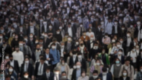Blurred defocused view of a people walking to work down the Tokyo street, with everyone moving in unison towards their destination. A birds eye view of density of population is overwhelming on city