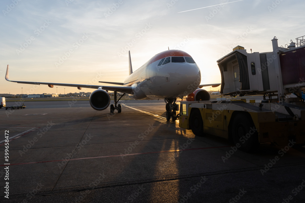 A jet bridge connecting to an airplane at sunset A jet bridge connecting to an airplane at sunset