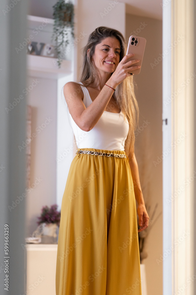 Blonde woman with long hair taking a photo with smartphone in front of mirror Blonde woman with long hair taking a photo with smartphone in front of mirror