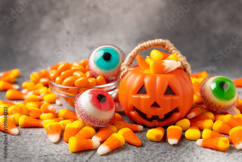 Halloween pumpkin-flavored corn candy  jelly eye  sugar skull and dragees on a black background. Classic sweet Halloween treats. Halloween holiday concept and Jack lantern.Place for text. 