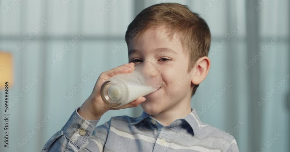 Cute Handsome child drinking milk.Healthy eating a child eating breakfast kid dream concept. Funny little boy in kitchen drinks yogurt milk and licks her lips.Positive kid smiling having breakfast. 4K Cute Handsome child drinking milk.Healthy eating a child eating breakfast kid dream concept. Funny little boy in kitchen drinks yogurt milk and licks her lips.Positive kid smiling having breakfast. 4K