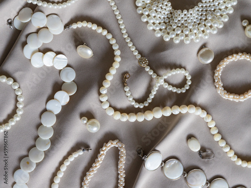 Many different pearl jewelry on a beige background. 