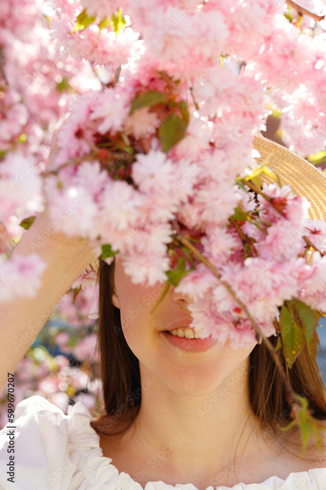 Obraz premium Close up. Young Gilrs Face Covered by Blooming Sakura Standing in the Parkl. Beauty Portrait. Femininity and Natural Beauty Concept