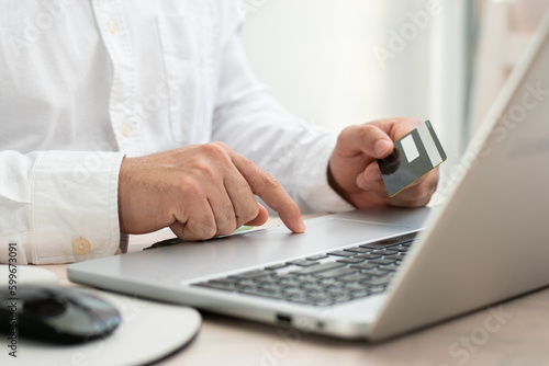 Close up of person touching their laptop while hold a credit card front the laptop for online shopping concept