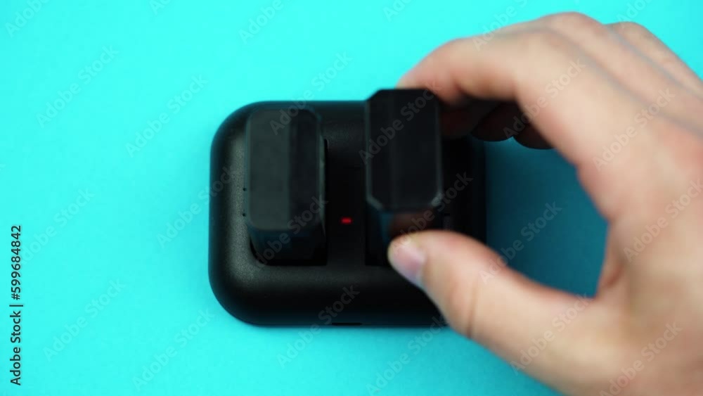 Person hands put black accumulators into special charger Person hands put black accumulators into special charger