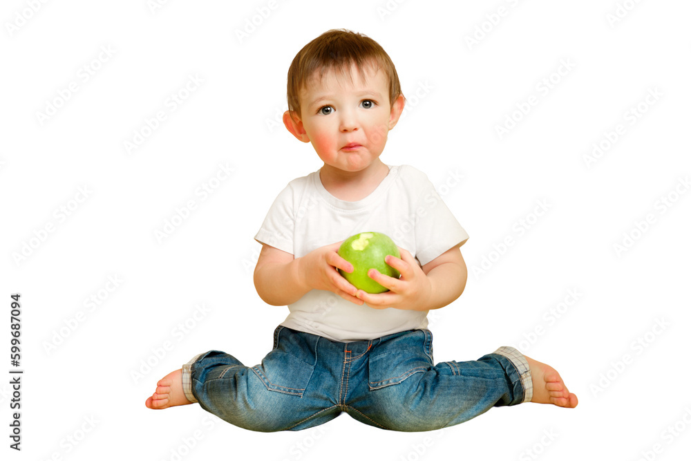 Toddler baby eats a sour apple on a studio isolated on a white background, surprised face. Child with a sour face in a white t-shirt and blue jeans. Kid aged one year and four months Toddler baby eats a sour apple on a studio isolated on a white background, surprised face. Child with a sour face in a white t-shirt and blue jeans. Kid aged one year and four months