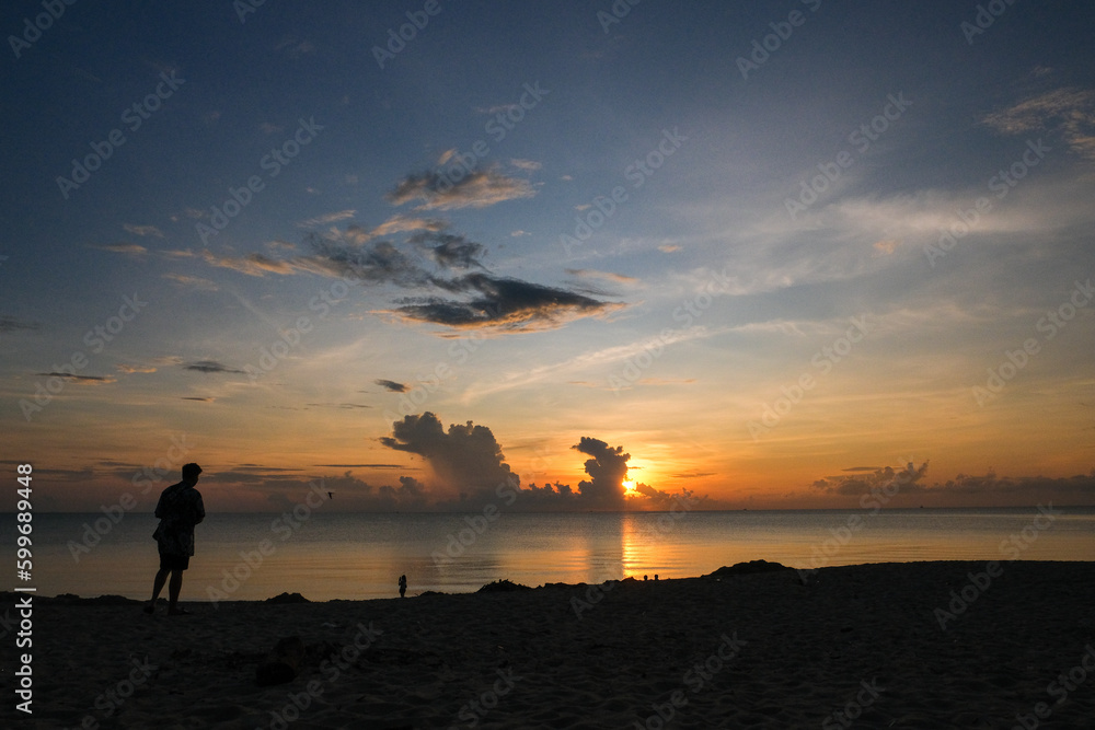 A person standing on the beach and seeing the sun rising from the sea horizon at East coast Terengganu, Malaysia.